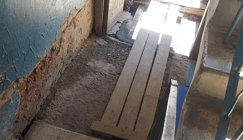Из-за разрушенных пола и лестниц жильцам приходится пробираться к своим квартирам по настилам из досок. 